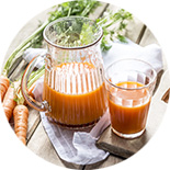 pichet et verre de jus de carotte sur une table en bois