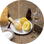 vinaigre blanc, citron et éponges posés sur une table en bois