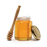 pot de miel ouvert et cuillère à miel sur un fond blanc