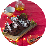 Petite bûche de Noël au chocolat et ses morceaux de chocolat plantés saupoudrés de sucre 