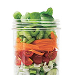 bocal en verre transparent rempli de crudités et légumes sur un fond blanc