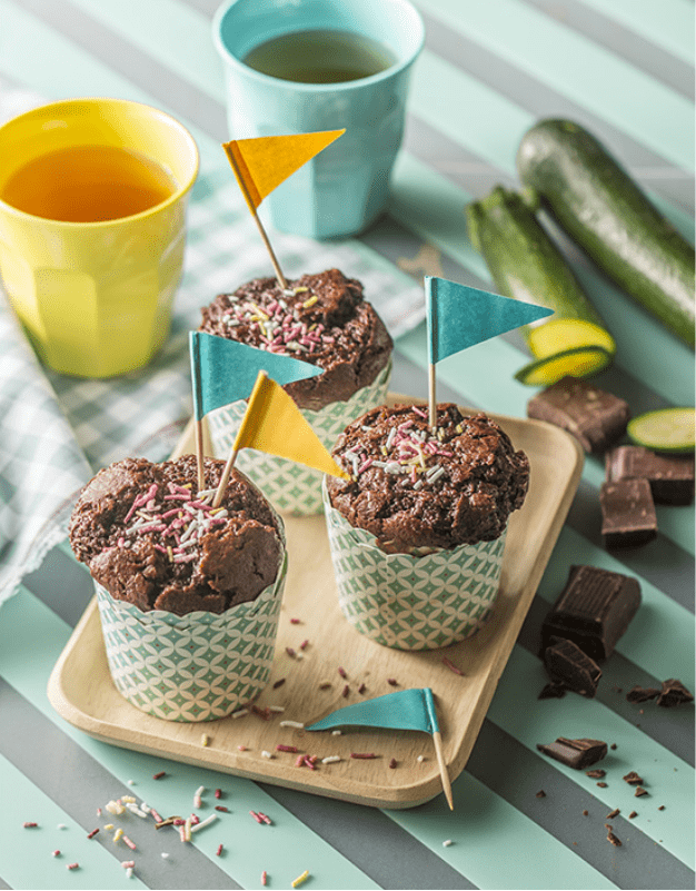 Trois muffins au chocolat sur une table et courgettes tranchées