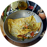 Omelette aux légumes dans une poêle posée sur une planche noire 
