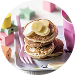 pile de pancakes et tranches de banane dans une assiette violette