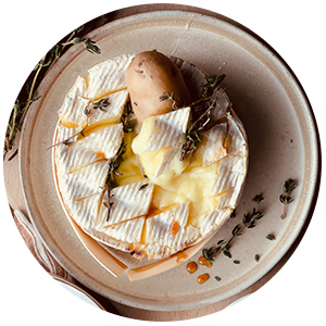 Camembert rôti dans une assiette avec brins de thym et pommes de terre