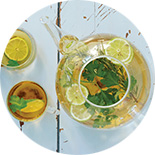 théière en verre avec thé glacé et tranches d'agrumes